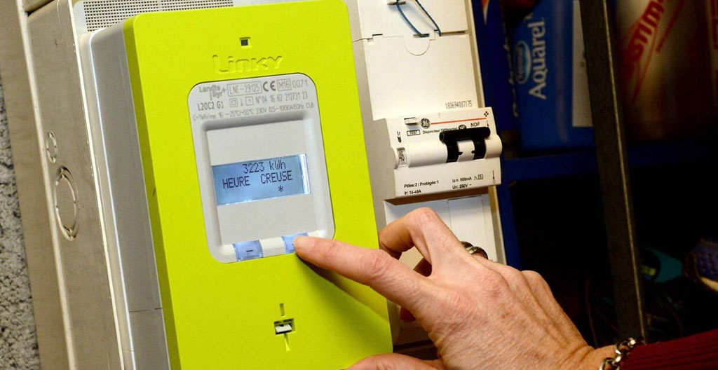 Compteur électrique communicant Linky professionnel installé sur tableau électrique dans un local commercial français, avec affichage numérique actif